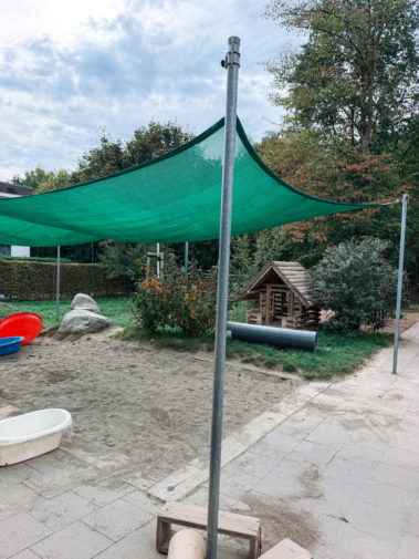 Sandkasten mit Sonnensegel und Spielhaus im Garten
